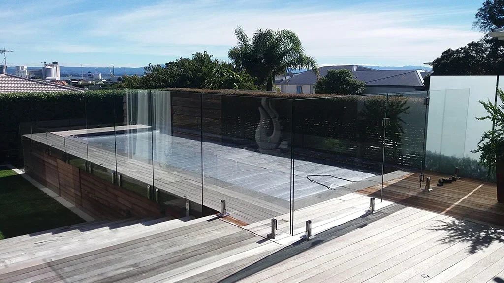 Frameless glass pool fence with stainless spigots around a pool on a timber deck in Tauranga